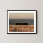 Haven art print of a serene coastal scene with a small building and ocean on Kangaroo Island, Australia, shown in a black frame on a wall.  
