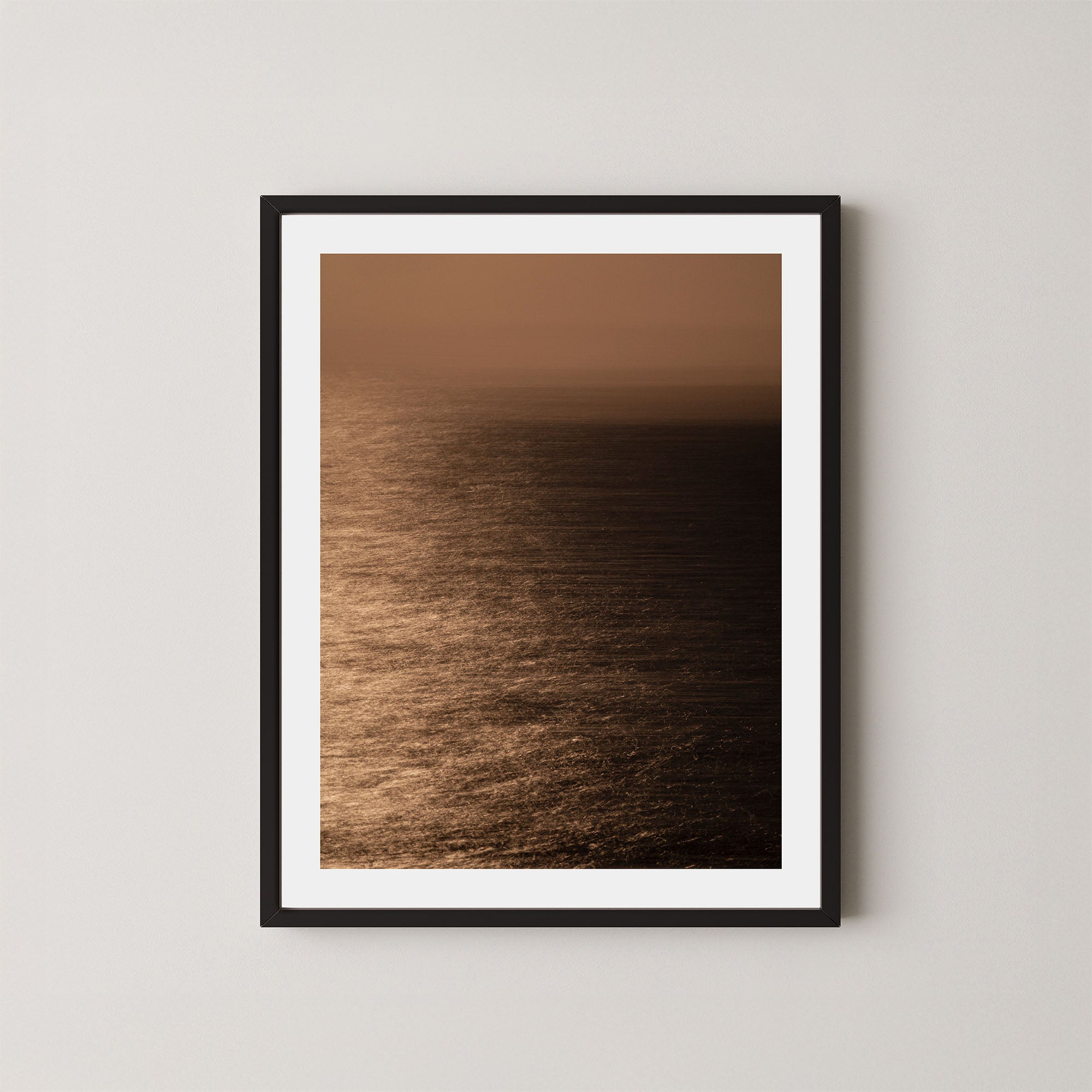 Art print of the Sydney ocean illuminated by moonlight, with rich golden and dark tones, shown on a wall in a black frame.