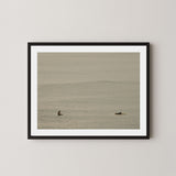 Ocean Therapy art print of two surfers on a calm ocean at Byron Bay, Australia, displayed on a wall in black frame.