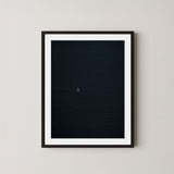 Voyage art print featuring a single sailing boat on the ocean, displayed on a wall in a black frame.