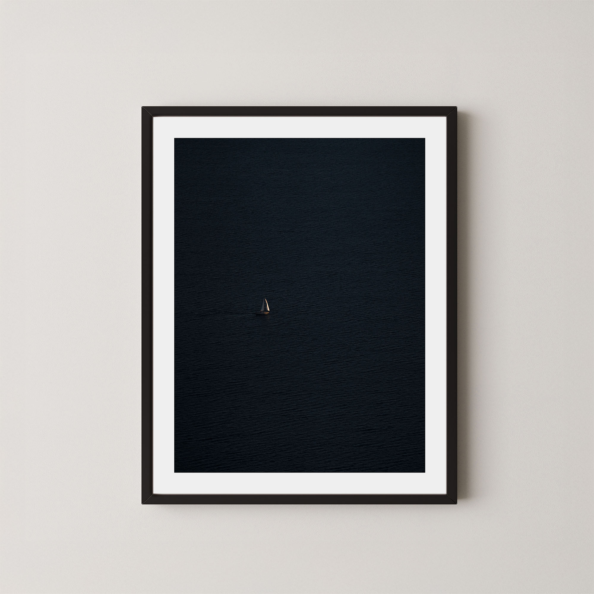 Voyage art print featuring a single sailing boat on the ocean, displayed on a wall in a black frame.