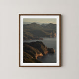 Freycinet art print showing an aerial view of the Tasmanian coastline and ocean at sunrise, displayed on a wall in a dark wooden frame.