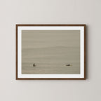 Ocean Therapy art print of two surfers on a calm ocean at Byron Bay, Australia, displayed on a wall in dark wooden frame.
