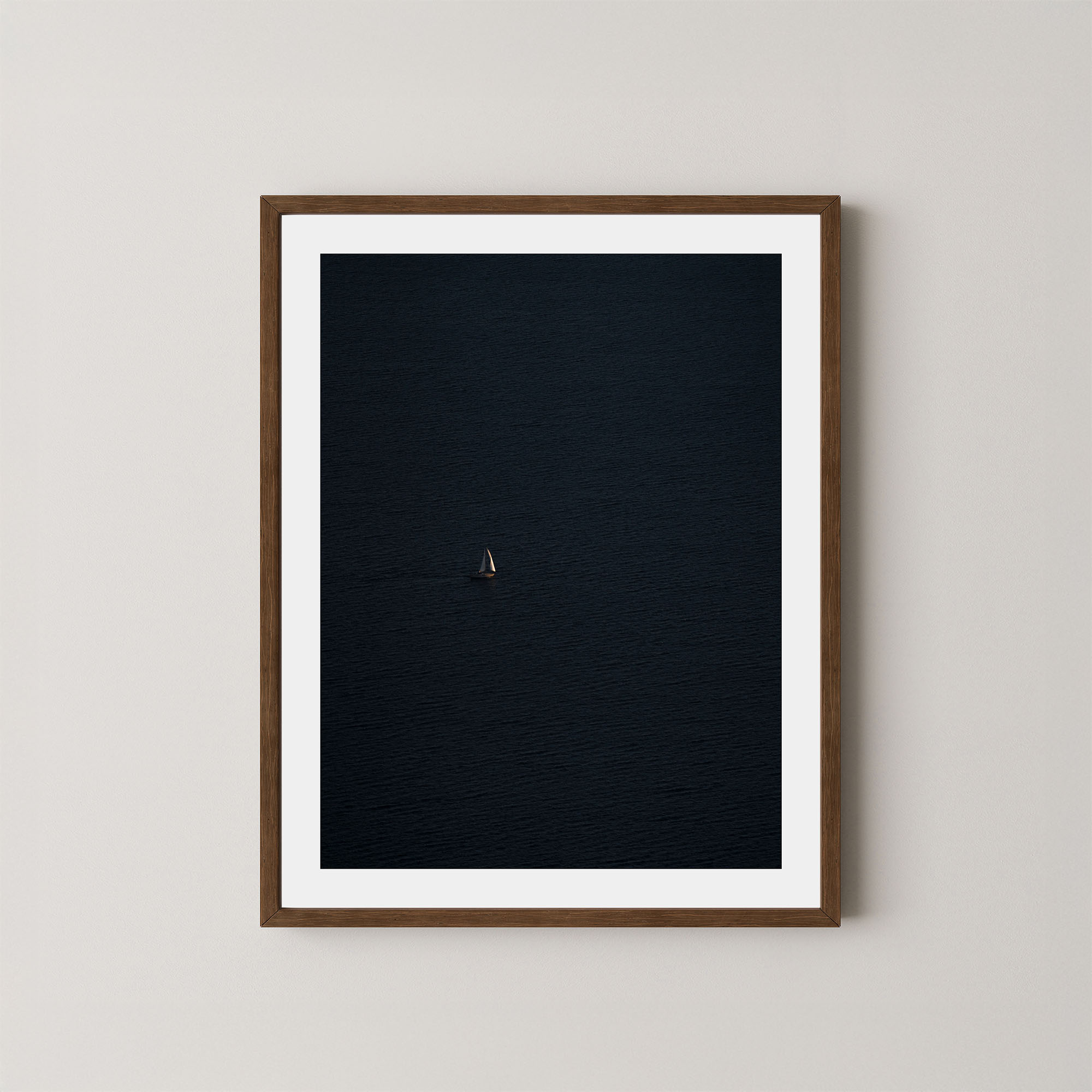 Voyage art print featuring a single sailing boat on the ocean, displayed on a wall in a dark walnut wooden frame.
