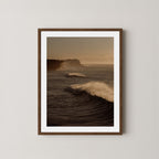 Wave Appreciation art print of Bronte, Sydney with waves and cliffs displayed on a plain wall in a dark walnut frame.
