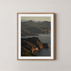 Freycinet art print showing an aerial view of the Tasmanian coastline and ocean at sunrise, displayed on a wall in a natural wooden frame.