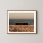 Haven art print of a serene coastal scene with a small building and ocean on Kangaroo Island, Australia, shown in a natural wooden frame.