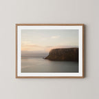 Silent Coast art print of a coastal cliff and sunrise in Stanley, Tasmania, displayed on a white wall in a natural wooden frame.
