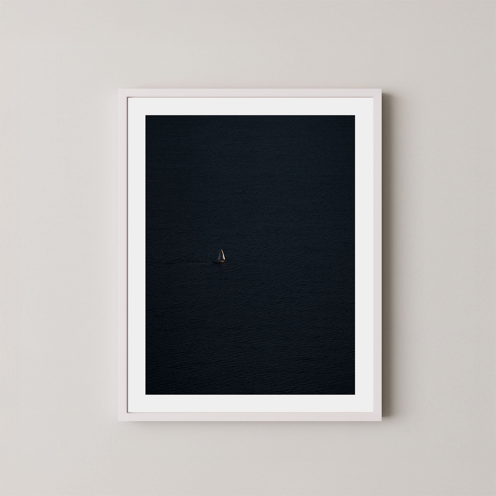 Voyage art print featuring a single sailing boat on the ocean, displayed on a wall in a white frame.