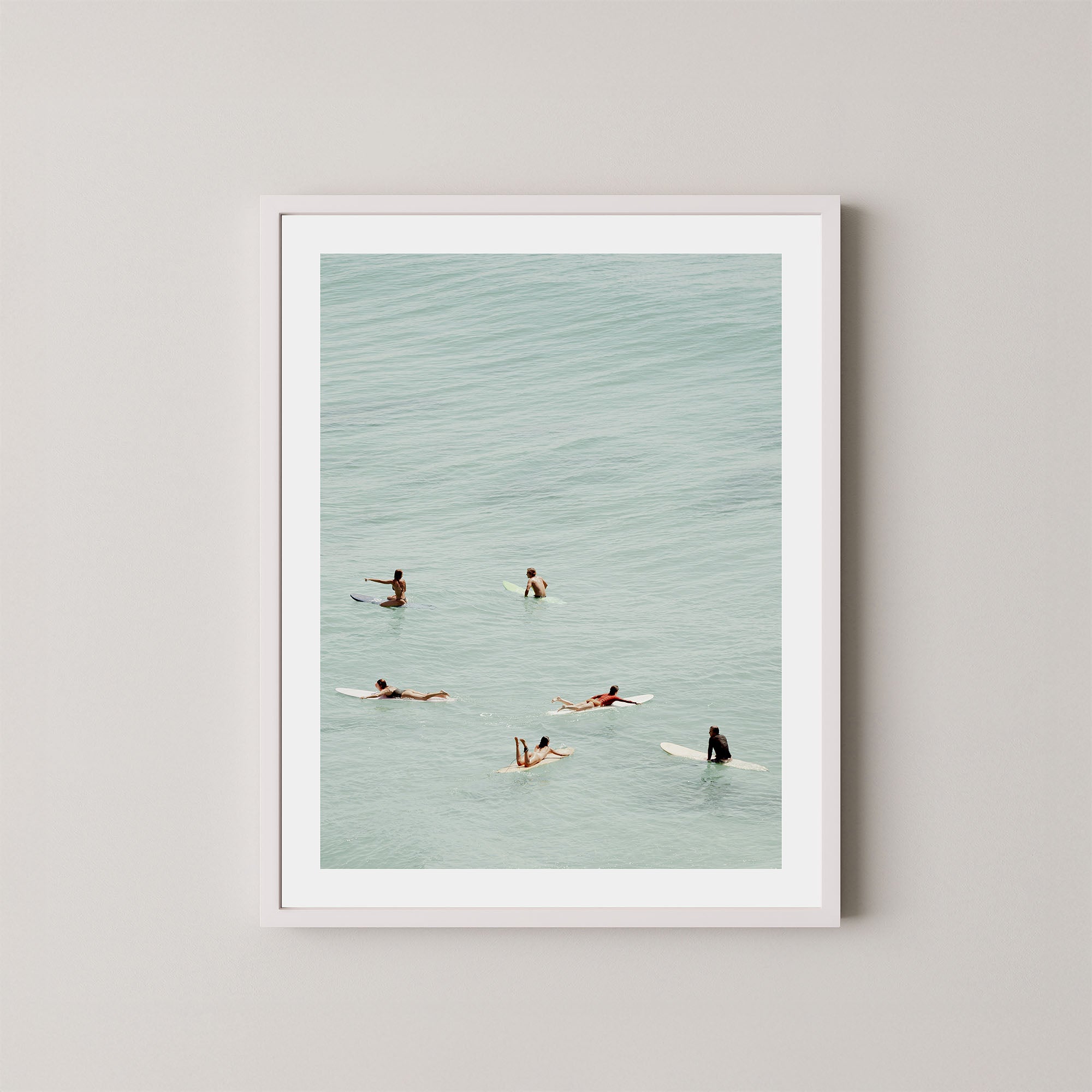 Fine photography artwork of people on surfboards in the water, displayed in a white frame. 
